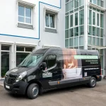 Fahrzeugbeklebung: Schwarzer Opel Movano mit Aufschrift Fugenlos Glücklich und Foto einer Frau in der Wanne